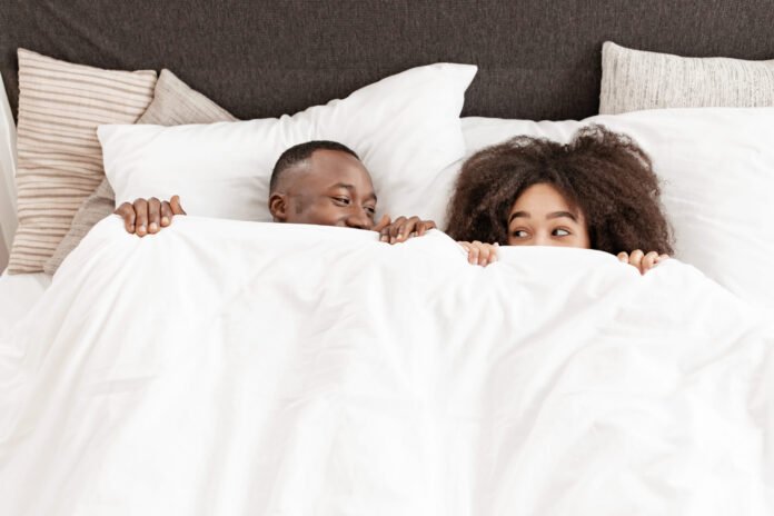 Romance and fun in comfortable bed, happy couple at home at weekend