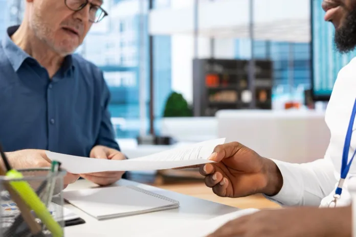 Older man reviewing financial paperwork with an adviser during a Pension Credit review