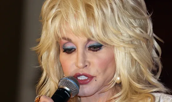 Dolly Parton Dolly Parton singing into a microphone during a live performance