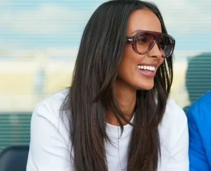 Maya Jama smiling while wearing oversized sunglasses