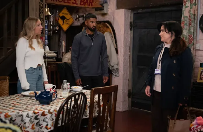 Belle Dingle and Kammy Hadiq standing with a victim liaison officer inside a cottage in Emmerdale.