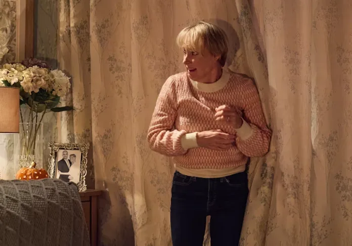 Sally Metcalfe looks startled while standing beside the curtains in her home during a Coronation Street Halloween storyline.