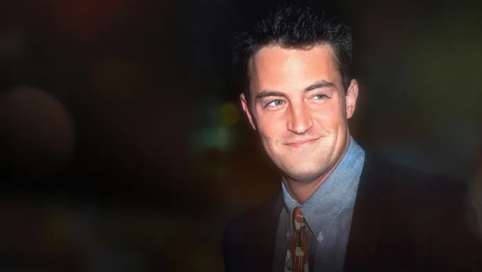 Young Matthew Perry smiling in a suit and tie in an archival photograph featured in Netflix's documentary The One About Matthew Perry.