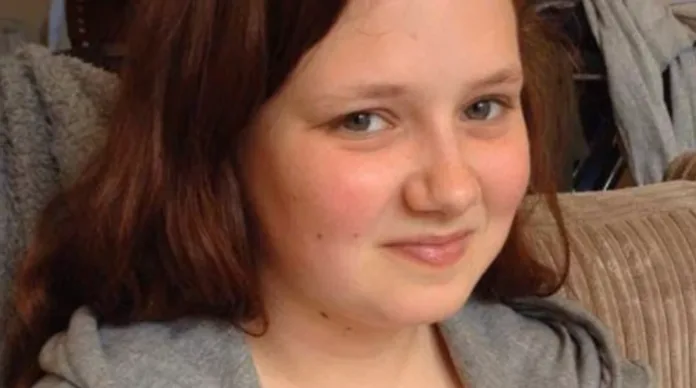 Leah Croucher wearing a grey hoodie and sitting on a sofa.