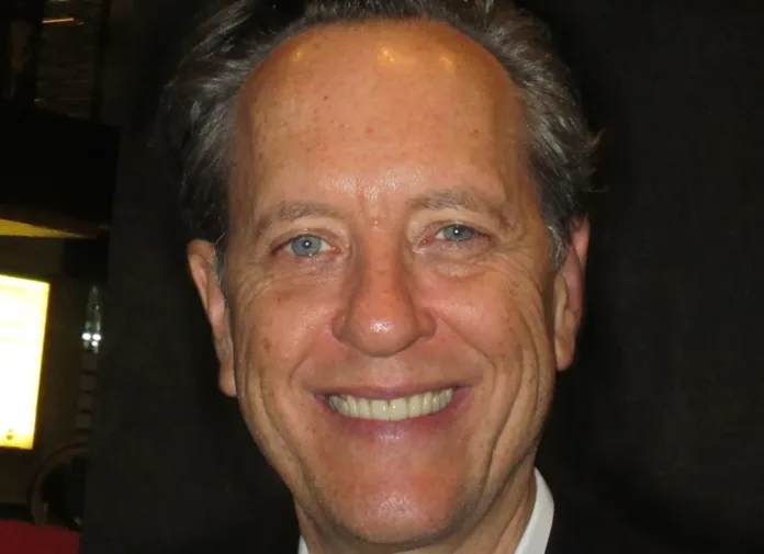 Richard E Grant smiling for a close-up photograph