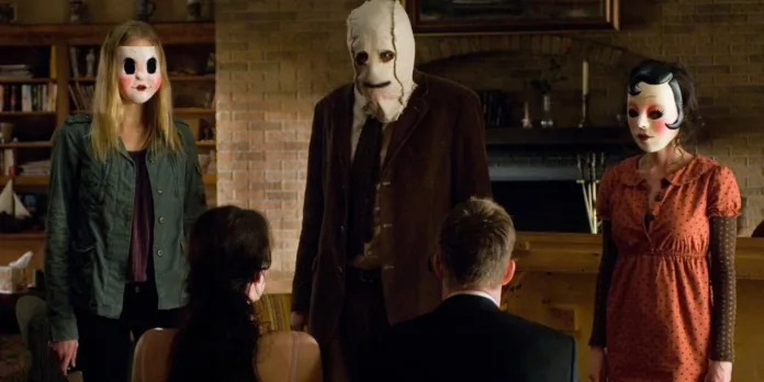 Three masked intruders confront Kristen McKay and James Hoyt inside a house in the 2008 horror film The Strangers.